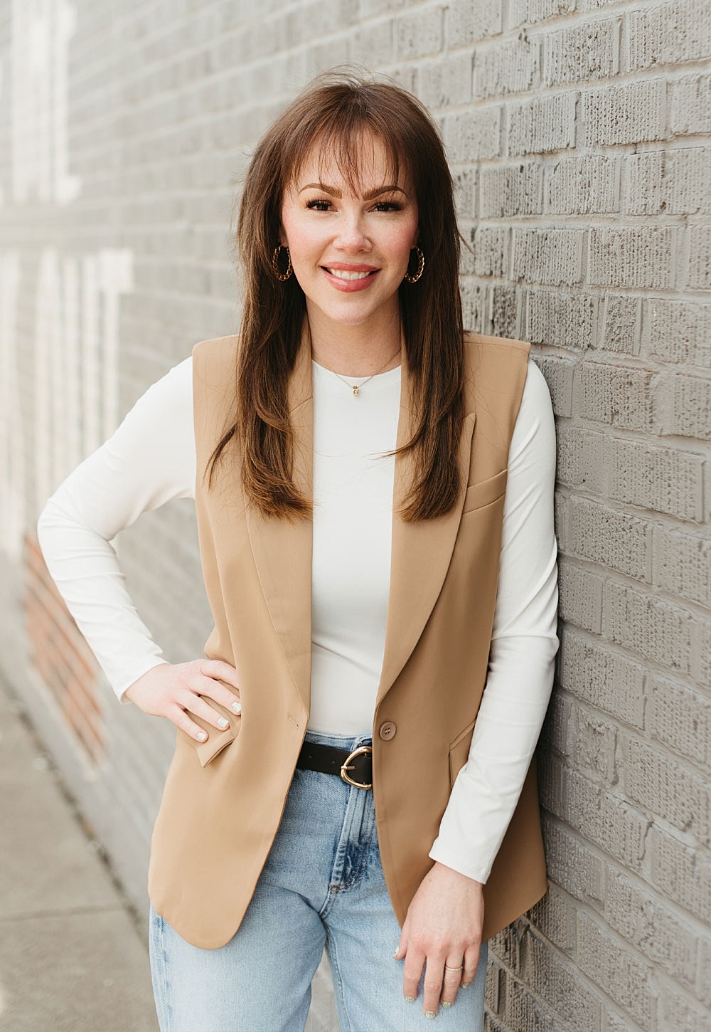Woman in stylish outfit leaning against wall.