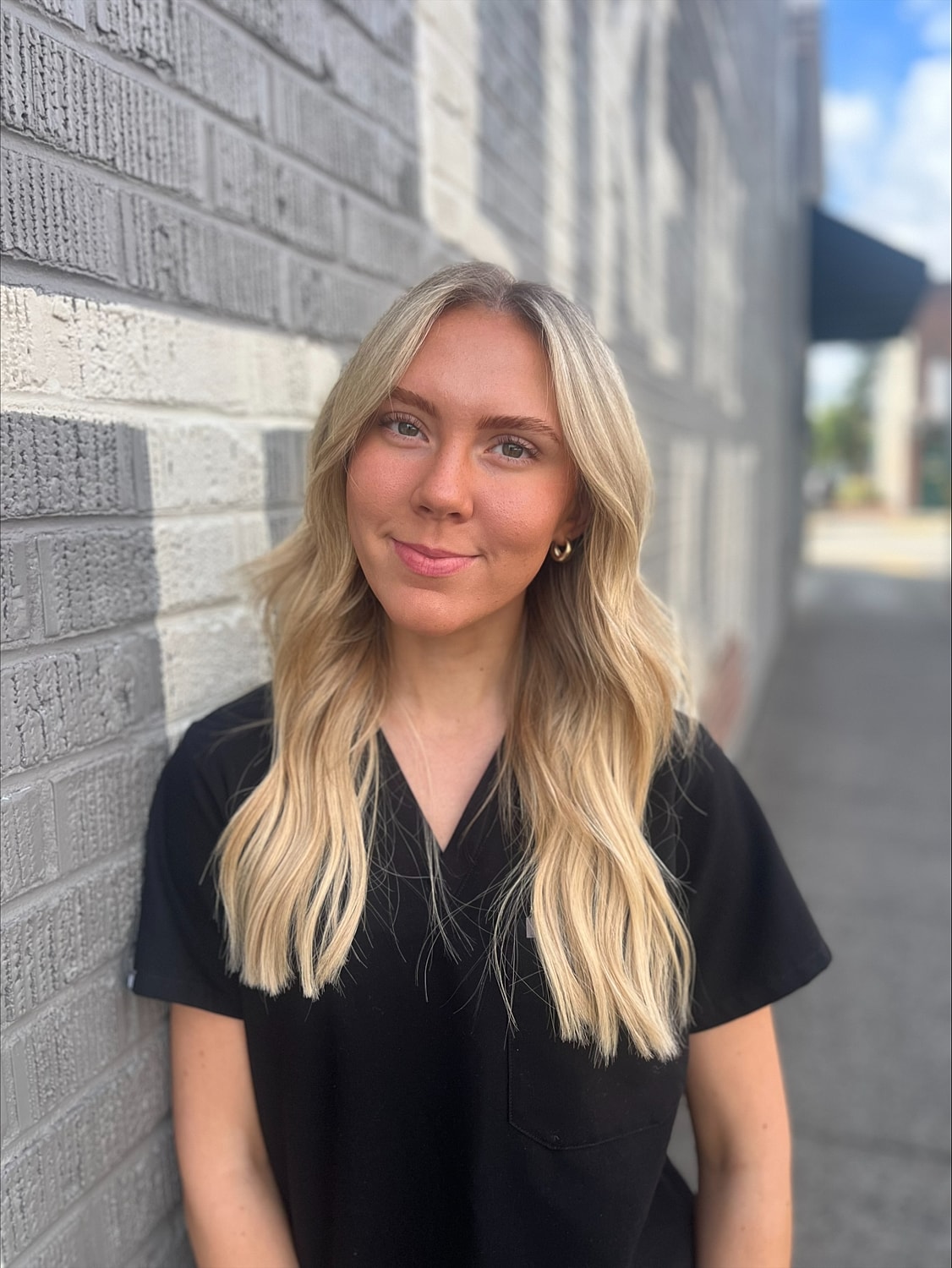 Person with long blonde hair against a wall